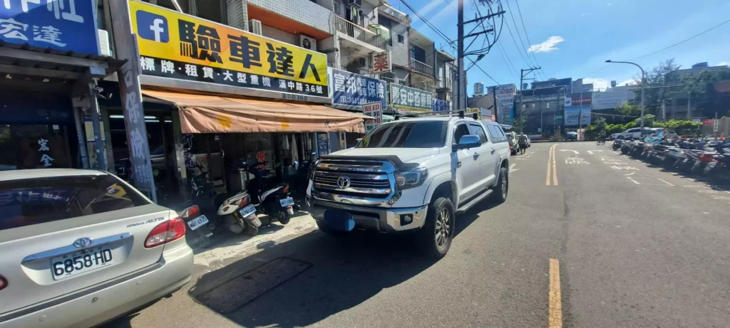 白色大型皮卡停在驗車達人店前